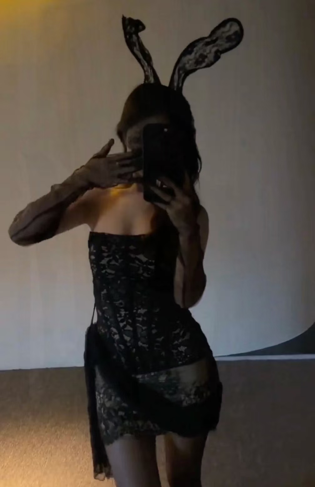 Woman in black lace bunny outfit with lace ears taking a mirror selfie